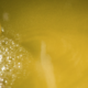 Primo piano di olio d’oliva appena estratto con presenza di morchia e bollicine superficiali, durante la fase di decantazione o filtrazione.