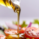 Olio d’oliva versato su un’insalata fresca composta da pomodori, cetrioli e verdure.