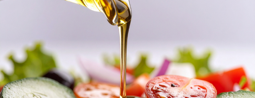 Olio d’oliva versato su un’insalata fresca composta da pomodori, cetrioli e verdure.